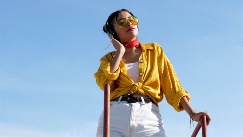 戴着耳机听音乐的时尚女孩轻轻摇摆身体实拍视频素材